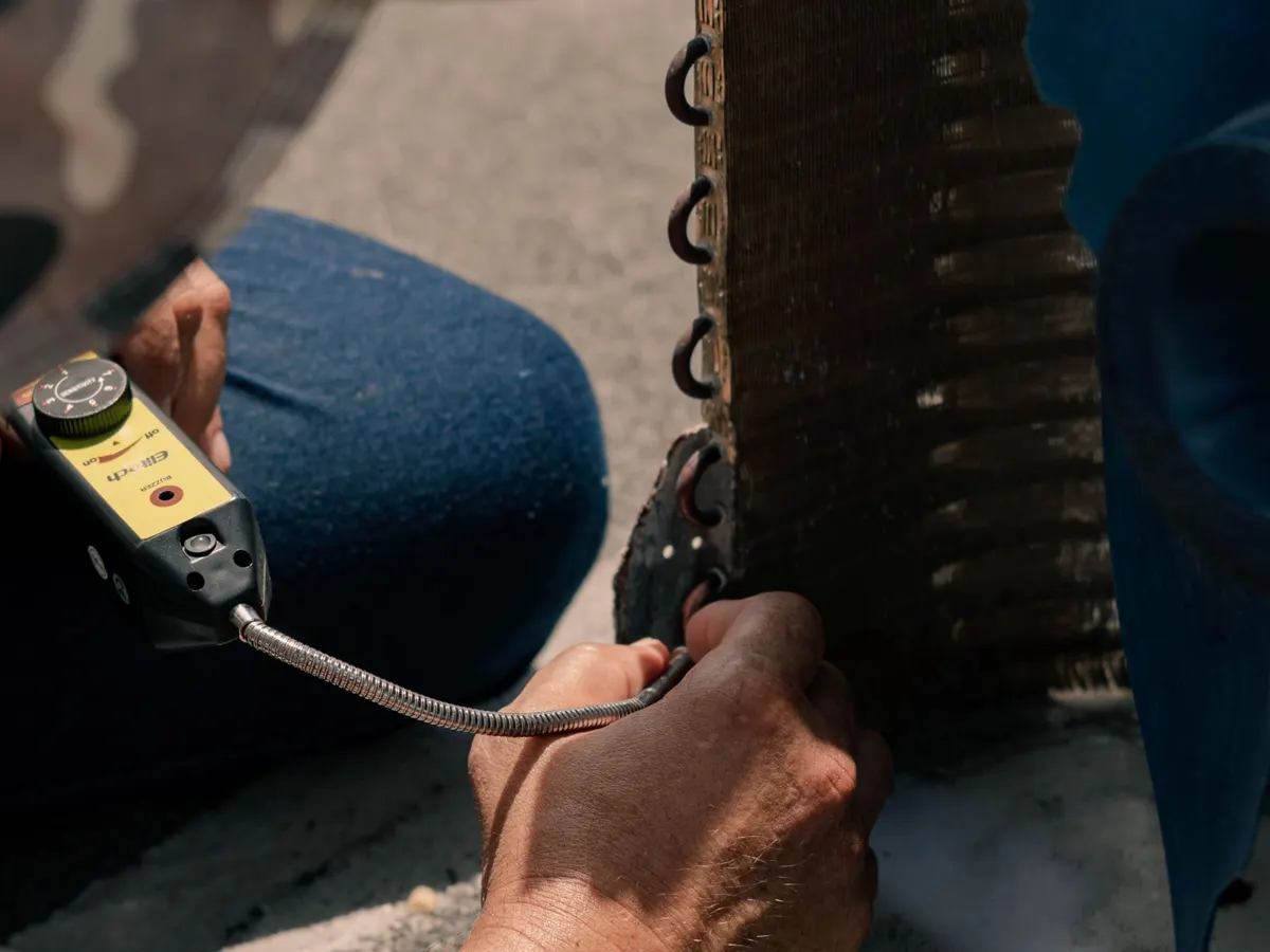 Technician repairing an outdoor air conditioning unit with hand tools