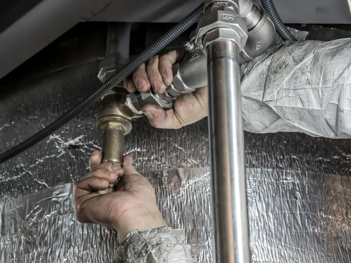 Hands tightening steel pipe fittings during a plumbing installation